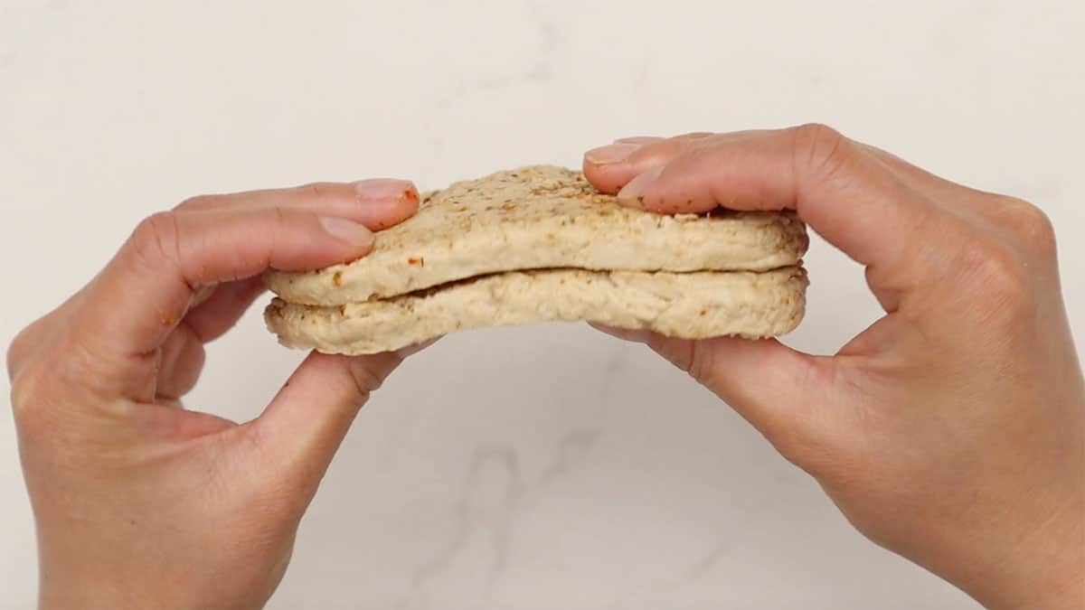 two hands pressing together vegan chicken cutlets to make a patty