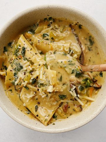 overhead of a bowl of vegan white lasagna soup with a spoon sticking out