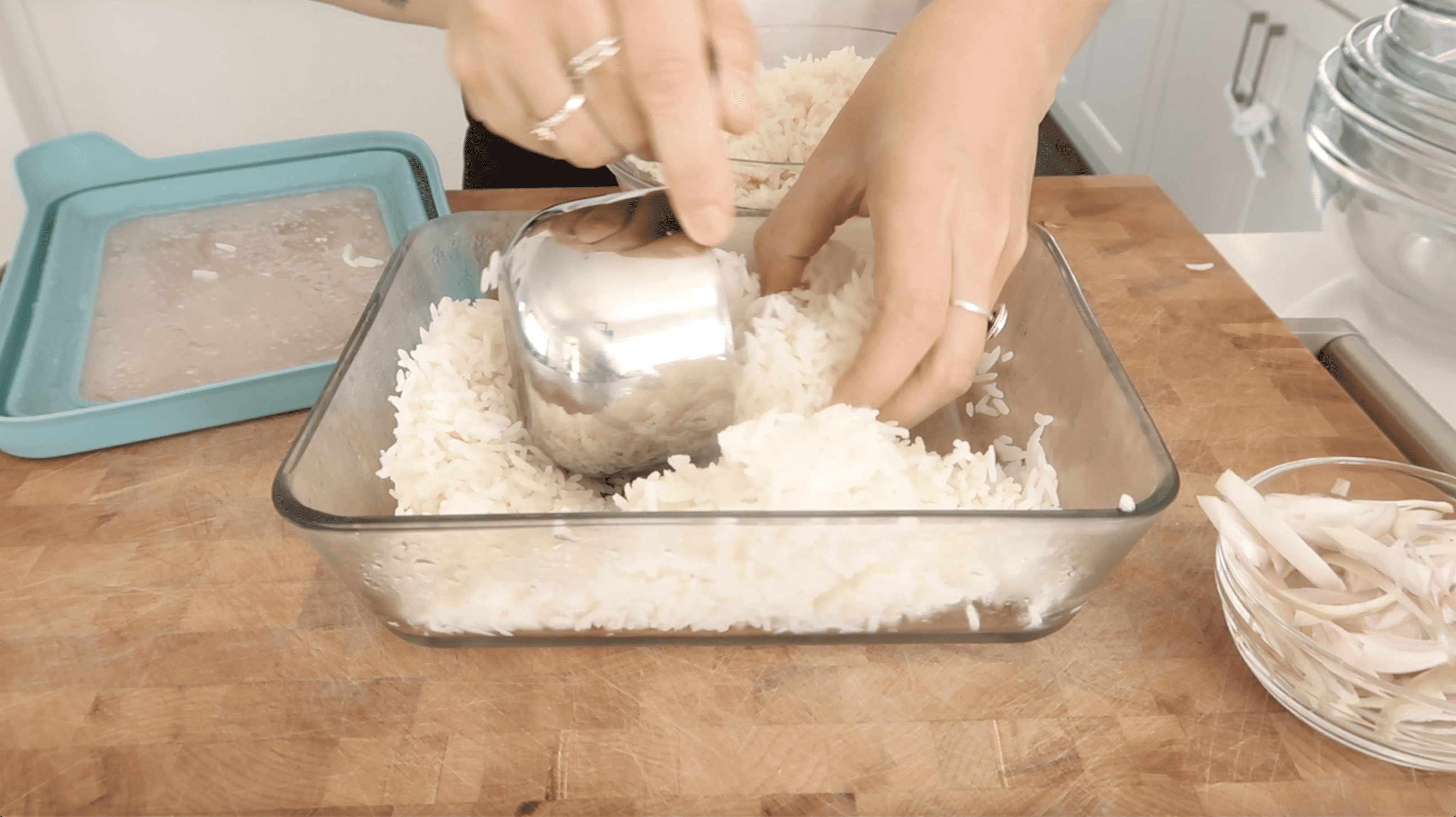 a glass container of rice with a measuring cup and hand portioning it out
