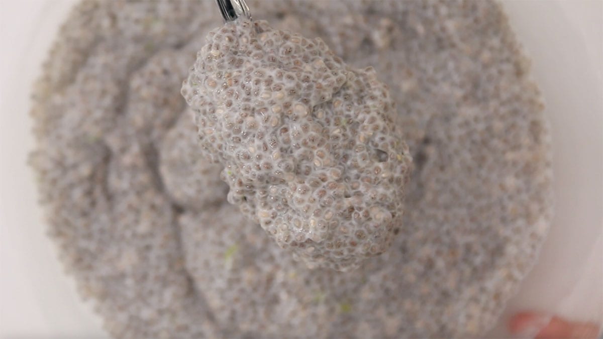 overhead of a mixing bowl with chia pudding in it and spoon lifting some up to show texture